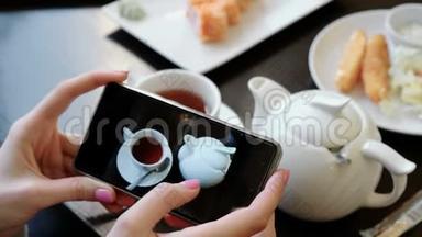 女人`手在<strong>手机屏幕</strong>上翻阅着茶杯和茶壶的<strong>照片</strong>。